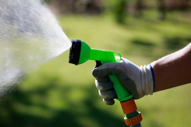 Hand watering the garden with a trigger nozzle