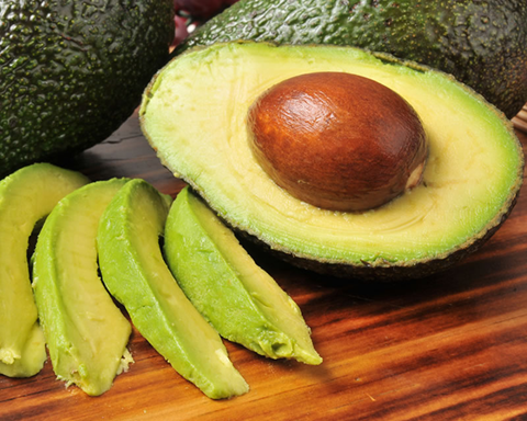 A ripe avocado fruit that has been cut and sliced 